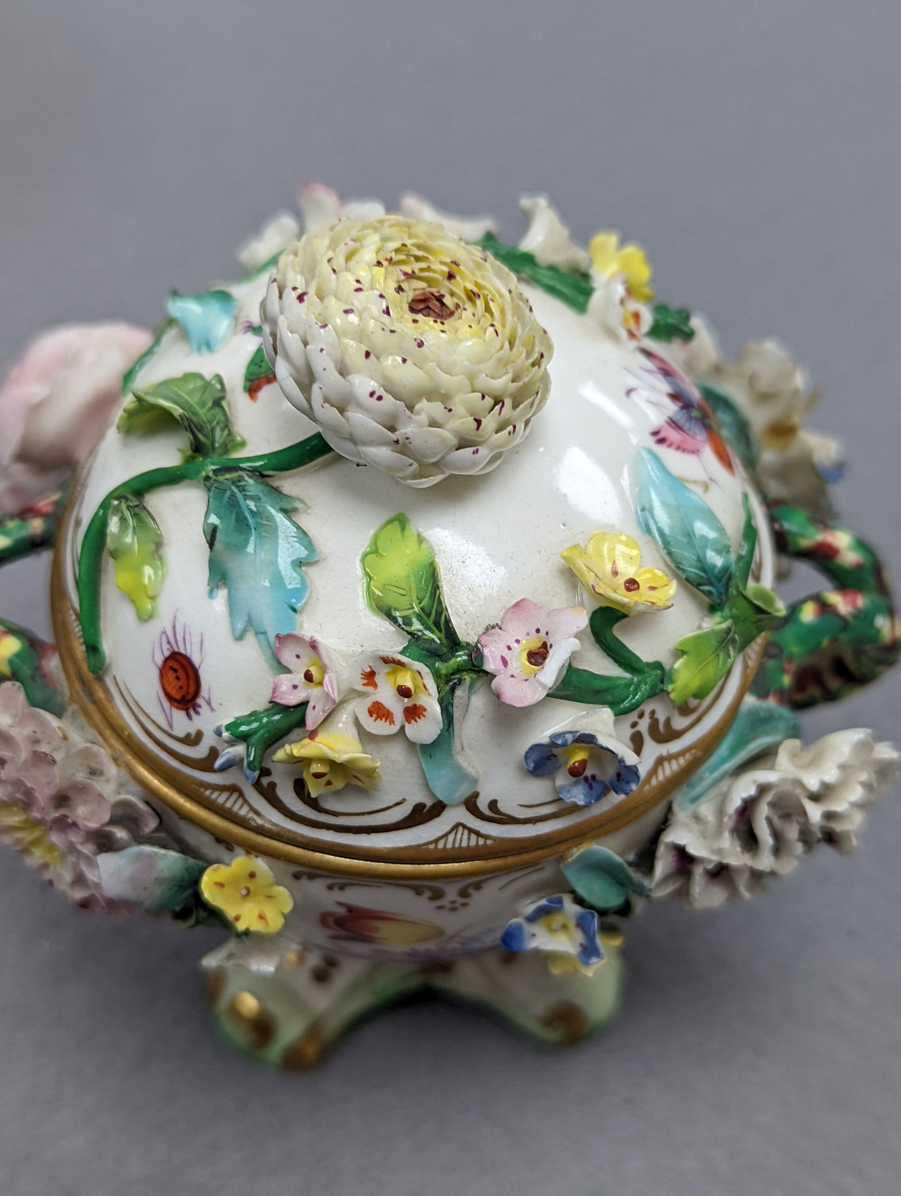 An 18th century Mennecy porcelain cup and cover, a Meissen style cup and cover, an English porcelain floral encrusted double inkwell and cover and a similar jar and cover